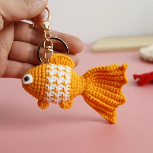 Handmade crochet goldfish keychain with orange and white yarn on a golden metal hook