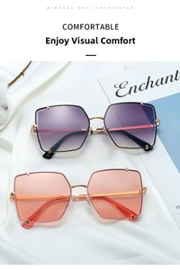 Dettagli di occhiali da sole oversize in metallo con lenti sfumate viola e rosa su seta