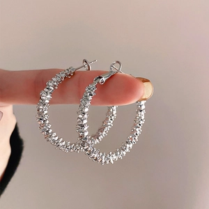 Close-up of textured silver hoop earrings featuring unique grainy metal finish on hand