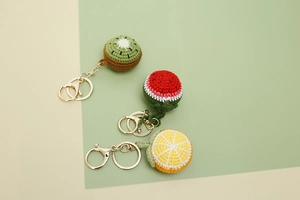 Detail von handgehäkelten Kiwi-, Wassermelonen- und Orangen-Anhängern mit goldenen Karabinern