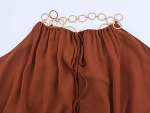 Detail eines rostroten Chiffonkleids mit goldenem Halsring und Kordelzug am Ausschnitt