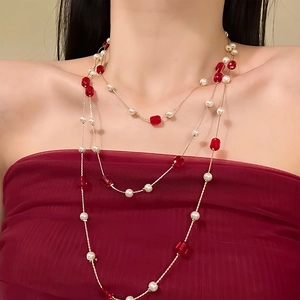 Elegant layered pearl necklace with deep red crystal beads on a golden chain