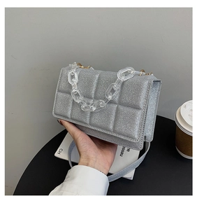 Détail du sac argenté pailleté avec matelassage et chaîne décorative en acrylique chic