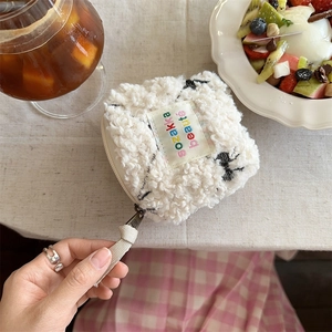Flat lay of a plush off-white cosmetic bag with embroidery on a checkered tablecloth