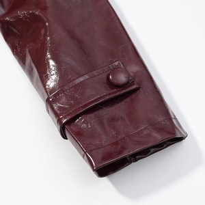 Dettaglio della manica in ecopelle bordeaux con trama plissettata e bottone decorativo