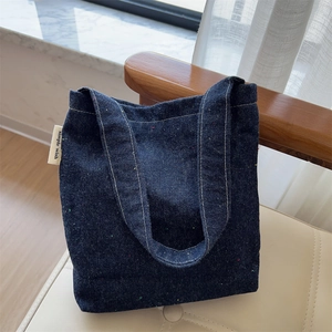 Close-up of blue denim tote bag with colorful fiber flecks and simple wish label