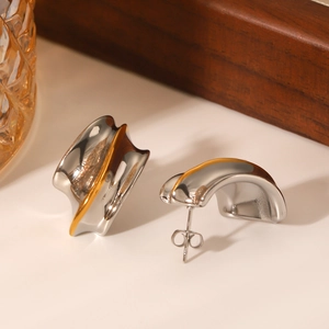 Detailed macro view of two-tone gold and silver stainless steel earrings on a soft background