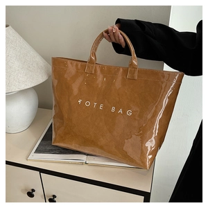 Brown gloss finish tote bag with white TOTE BAG text shown on a cream cabinet