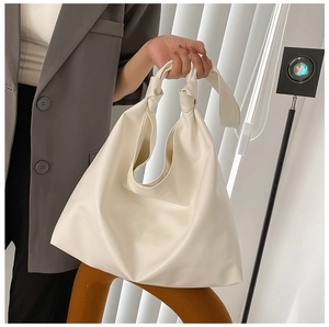 Detail of a cream-white tote bag with a unique knot-handle design for daily wear