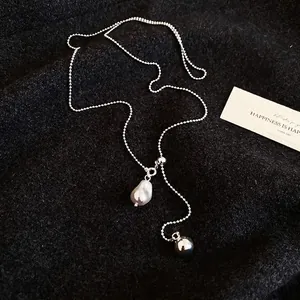 Baroque pearl and silver ball necklace on black textured background elegant jewelry