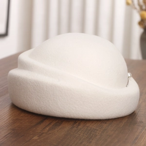 Détail d'un béret en laine blanche orné d'une perle élégante et d'une chaîne argentée