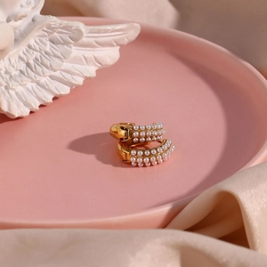 Detailed shot of double-row pearl gold hoop earrings on a decorative ceramic tray