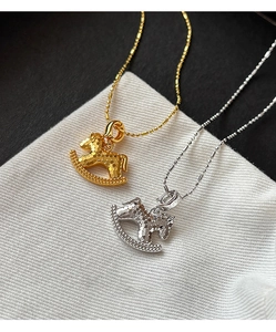 Macro detail of 18k gold and silver plated rocking horse pendants with scale texture
