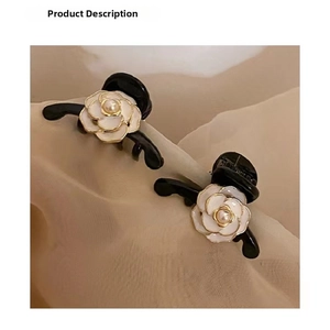 Close-up of black hair claws featuring white camellia flowers and center pearl details