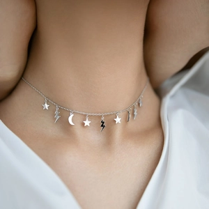 Detailed close-up of a silver choker with star, crescent moon, and lightning bolt charms