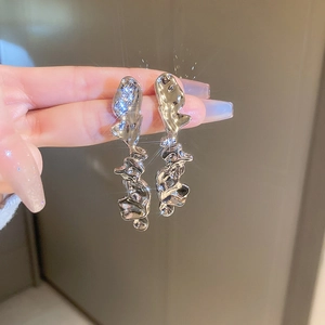 Close-up of irregular silver liquid metal earrings with a glossy shimmering finish
