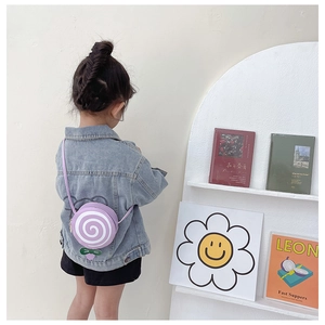 Detail of a purple lollipop-shaped kids crossbody bag with white spiral and green leaf