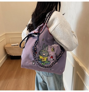 Detail of purple canvas tote with cartoon rabbit and braided bicolor rope strap