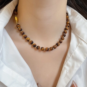 Detail of tiger eye beaded necklace with gold spacers worn on a white shirt collar