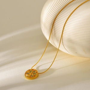 Close-up of gold-plated life tree pendant with blue stones on a thin snake chain
