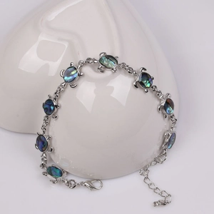 Turtle bracelet with colorful abalone shell inlay displayed on a white porcelain plate