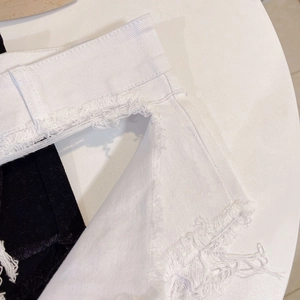 Gros plan sur les ourlets effilochés et le denim blanc et noir de ce mini short