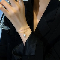 Detalle de la pulsera de doble capa de oro y perlas lucida con un traje negro