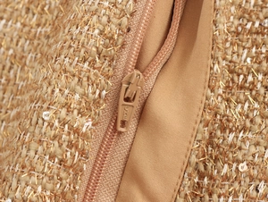 Detailed macro view of the gold-threaded tweed fabric and branded metal zipper closure