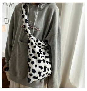 Detail of soft plush cow print crossbody bag with high-capacity design shown on model