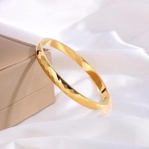 Detailed view of golden hammered titanium steel bracelet on white silk luxury background