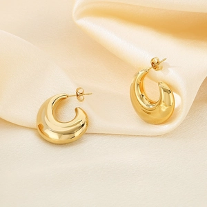 Boucles d'oreilles créoles C dorées 18K sur fond élégant en satin jaune soyeux