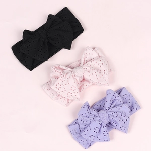 Detailed view of hollow fabric baby headbands with large bows in black, pink and purple