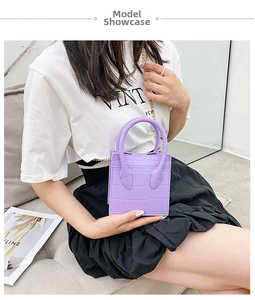 Close-up of a purple crocodile-patterned mini handbag with a golden chain strap on a model