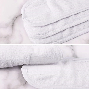Detail of white terry cloth headbands with adjustable velcro closure on marble surface