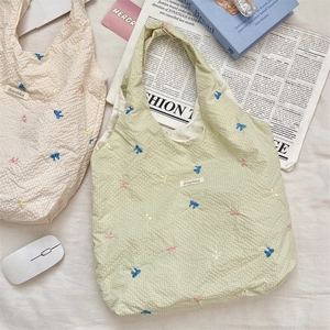 Détail de nœuds colorés brodés sur la surface d'un sac cabas en toile vichy vert