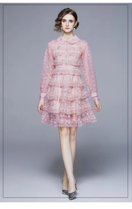 Détail de robe en dentelle rose avec broderie lourde et jupe à volants multicouches