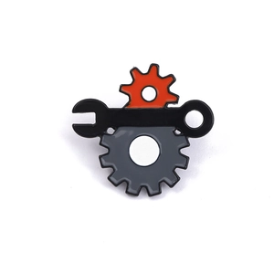 Detail of an industrial enamel pin showing a red gear and black wrench on white background