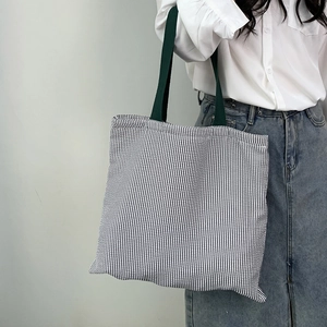 Detailed view of large canvas tote bag with vertical stripes and wide green shoulder strap