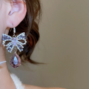 Close-up of butterfly earring with sparkling zircons and a purple teardrop pendant