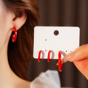 Close-up of elegant red C-shaped hoop earrings worn by a model with display card