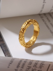 Close-up of golden irregular lava texture ring displayed on a minimalist magazine page