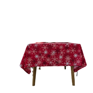 Red Christmas tablecloth with festive white snowflake patterns on a wooden table