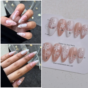 Detail of almond press-on nails featuring winter snowflakes and sparkling silver rhinestones