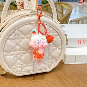 Cute bunny ice cream keychain with orange beads and bell attached to a white quilted bag