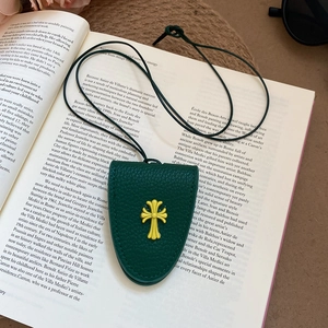 Detail of dark green pebble leather magnetic glasses clip with yellow cross on a book