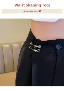 Close-up of golden waist pin with star and heart icons on black trousers waistline