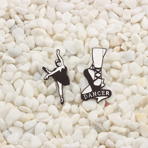 Detail of ballet dancer silhouette and dancer text enamel pins on white stone background