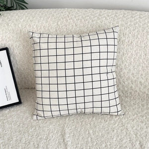 Detail of minimalist black and white checkered cotton linen cushion cover on a sofa