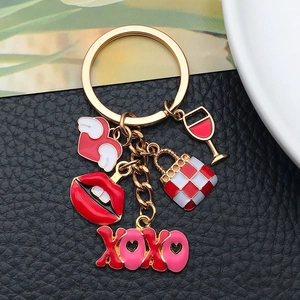 Detail of gold keychain with XOXO charm, red lips, heart wings, and enamel handbag pendant