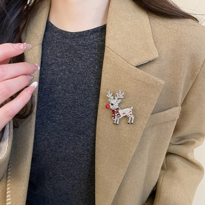 Detail of reindeer brooch with crystal inlay and red scarf on beige blazer lapel